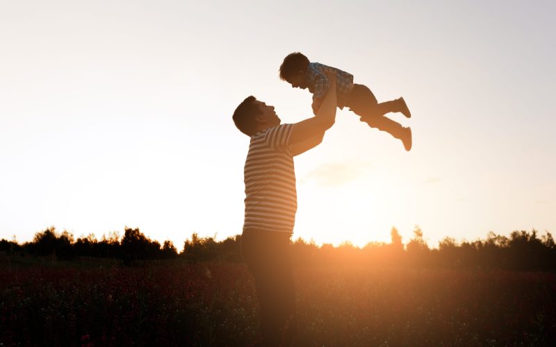 Father and son playing in the park at the sunset time. Happy family having fun outdoor.